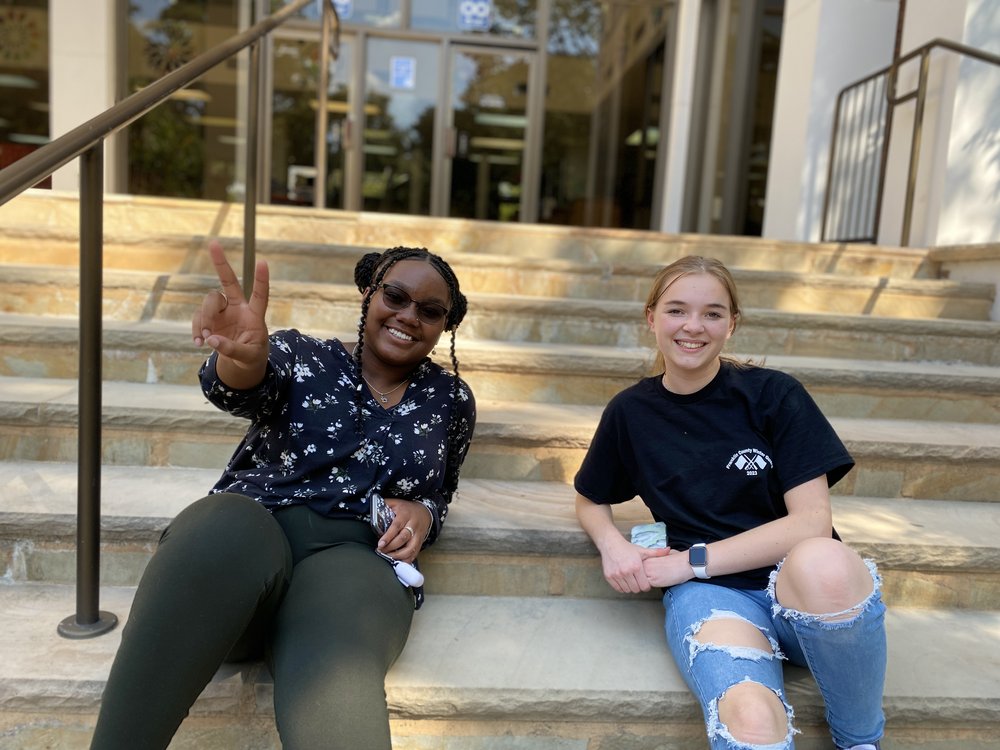 Two students sitting in front of school.